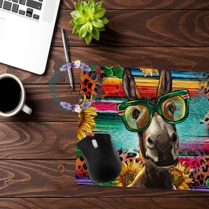 May include: A colorful mouse pad with a donkey wearing green sunglasses and a colorful background. The background features a rainbow stripe pattern, sunflowers, and cactus.