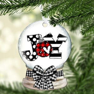 May include: A white snow globe ornament with a black and white checkered bow. The globe features the word "JOY" in black and white with a red and black buffalo plaid ornament in the center.