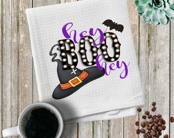 May include: White kitchen towel with a purple and black design that says "Hey Boo Hey" with a witch's hat and a bat.