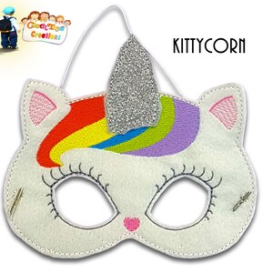May include: A white felt unicorn mask with a rainbow horn and pink ears. The mask has a silver glitter horn and is decorated with black embroidery. The mask has elastic straps for wearing.