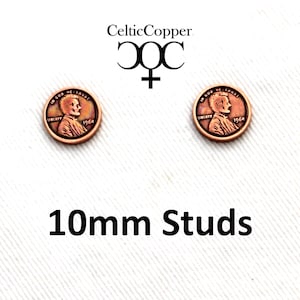 May include: A pair of copper penny stud earrings. Each earring features a 1964 penny with the words "In God We Trust" and "Liberty." The earrings are 10mm in size. The CelticCopper logo is in the upper left corner.
