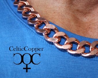 Puede incluir: Un collar de cadena de cobre grueso con un diseño de eslabón plano y ancho. La cadena se lleva sobre una camisa azul con el texto "CelticCopper" y un símbolo.