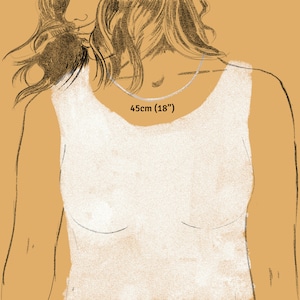 May include: A silver necklace, 18 inches (45cm) long, is displayed around a person's neck. The image is an illustration with a warm, neutral background. The text "45cm (18")" is visible near the necklace.
