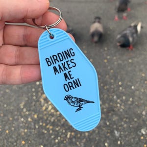 May include: A light blue motel key chain with the text "Birding Makes Me Orni" and a small black silhouette of a bird.