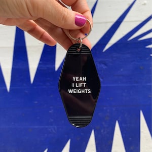 May include: Black motel key chain with the text "YEAH I LIFT WEIGHTS" in white lettering.