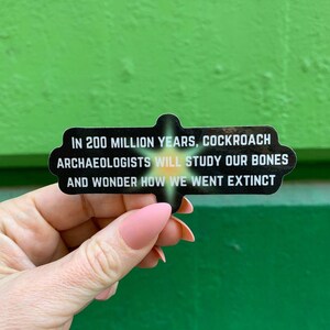 Könnte beinhalten: Ein schwarz-weißer Aufkleber mit dem Text "IN 200 MILLION YEARS, COCKROACH ARCHAEOLOGISTS WILL STUDY OUR BONES AND WONDER HOW WE WENT EXTINCT".