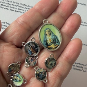 Pu&ograve; includere: Una collezione di ciondoli religiosi con immagini di figure e scene religiose. I ciondoli sono rotondi e ovali, con montature in metallo color argento. Le immagini sono colorate e dettagliate, raffiguranti vari eventi biblici.