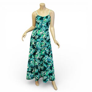 May include: A long, flowing dress with a floral pattern in shades of teal, green, and white. The dress features a scoop neckline, spaghetti straps, and a fitted bodice that flows into a full skirt. The dress is displayed on a mannequin.
