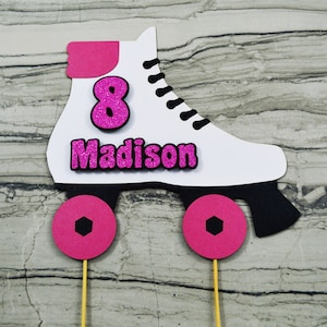May include: White roller skate cake topper with pink wheels and a pink number 8 and the name Madison in pink glitter letters.