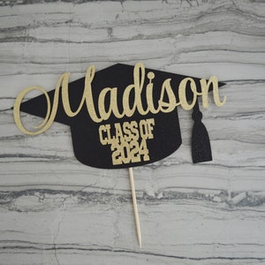 Graduation cap shape glitter cake topper personalized with name across the top and Class of 2024 along the bottom.