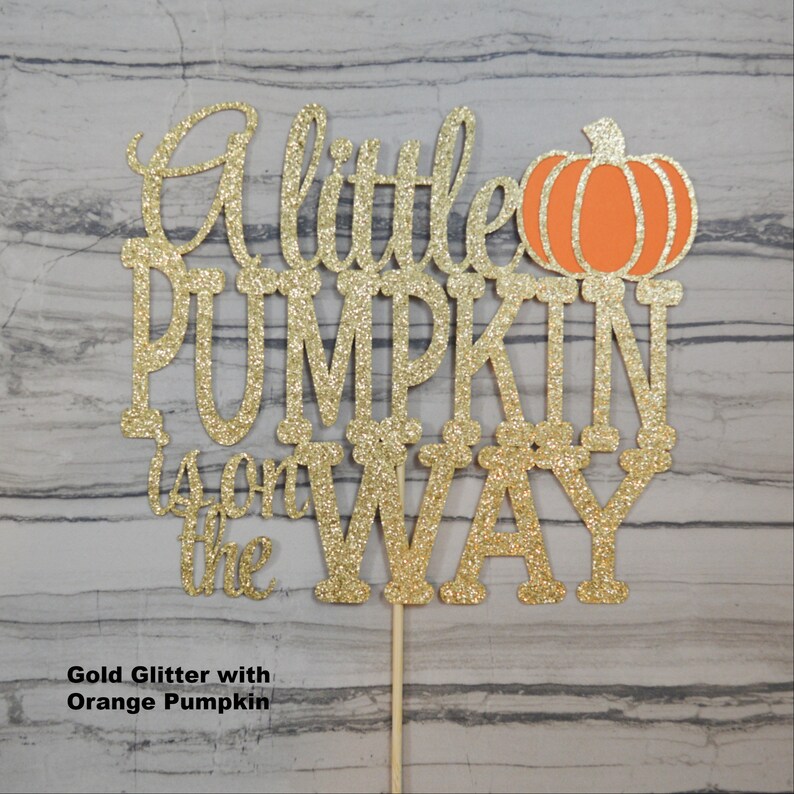 Puede incluir: Adorno para tarta con purpurina dorada con la frase "A little PUMPKIN is on the WAY" y una calabaza naranja. El adorno est&aacute; sujeto a un palito de madera para insertarlo f&aacute;cilmente en una tarta.