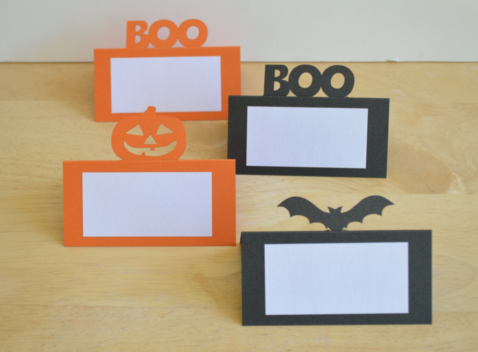 A BOO Cutout Above a Rectangular Name Panel Halloween place cards with BOO lettering, pumpkin and bat-shaped top details.
