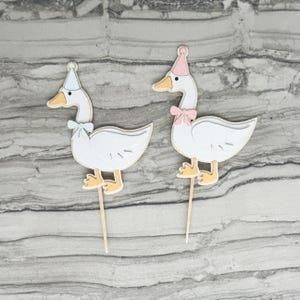 Two goose cupcake toppers shown in light pink and light blue accent color options.
