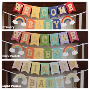May include: Three rainbow baby banners with the words "Welcome Baby" in gold glitter letters. The banners are in three different color schemes: primary colors, dark pastels, and light pastels.