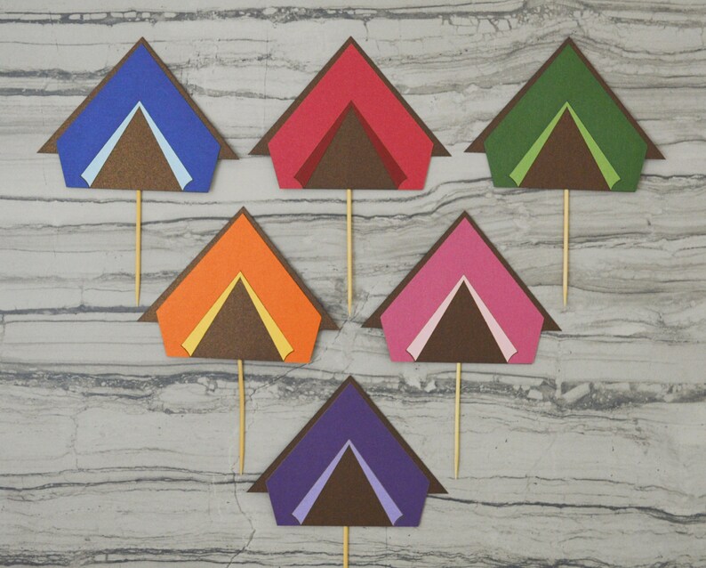 May include: Six colorful paper tent cupcake toppers. The tents are made of different colors, including blue, red, green, orange, pink, and purple. Each tent has a brown flap and a white or yellow interior.