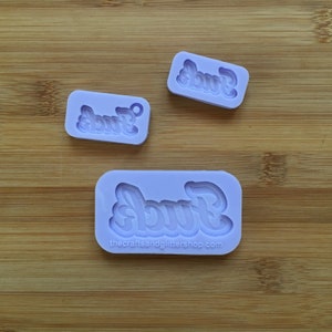 Peut inclure: Trois moules en silicone violet pour la fabrication d'objets en résine. Chaque moule présente le mot "F*ck" dans une police de caractères stylisée. Le plus grand moule porte le texte "thecraftsandglittershop.com" en bas.