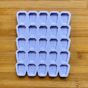 Könnte beinhalten: Eine lilafarbene Silikonform mit 36 einzelnen Vertiefungen in Form von Kaffeetassen. Die Form befindet sich auf einer Holzoberfläche.
