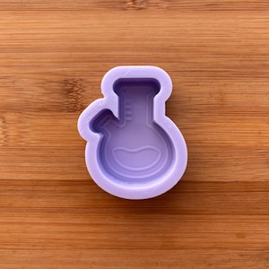 Könnte beinhalten: Eine hellviolette Silikonform in Form eines Laborflaschenkörpers mit rundem Boden und schmalem Hals. Die Form hat ein kleines Seitenrohr und ist für Bastel- oder Harzprojekte konzipiert.