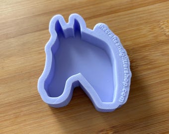 Könnte beinhalten: Ein hellvioletter Ausstechform in Form eines Pferdekopfes mit 3D-gedruckter Textur. An der Seite des Rahmens befindet sich der geprägte Text thecraftsandglittershop.com. Das Objekt hat eine hohle Mitte und einen erhöhten Rand zum Ausstechen.