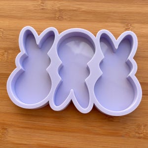 Può includere: Uno stampo a forma di coniglietto a tre cavità, di colore viola chiaro, per il fai-da-te. Lo stampo presenta un contorno continuo con tre forme di coniglietto distinte, perfetto per creare dolcetti o oggetti artigianali a tema pasquale.