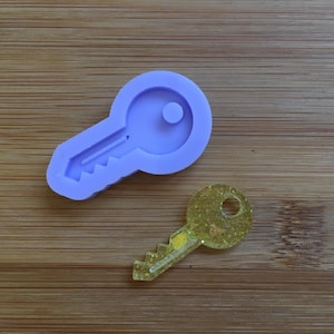 Puede incluir: Un molde de silicona morado con forma de llave y un dije de llave con brillo amarillo.