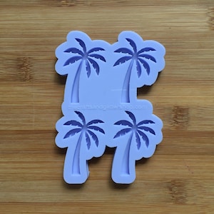 Puede incluir: Un molde de silicona morado con cuatro formas de palmeras. El molde está diseñado para hacer decoraciones para pasteles, galletas u otros postres.
