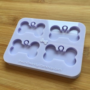 Op de afbeelding: Een lichtpaarse siliconen mal met vier botvormige uitsparingen, elk met een klein rond gaatje voor een bedelringetje. Een klein boticoontje staat in het midden tussen de uitsparingen en de tekst thecraftsandglittershop.com staat onderaan in reliëf.