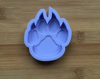 May include: A light purple silicone mould shaped like an animal paw print. The mould features a large central pad and four smaller toe pads, with a smooth, matte finish and raised edges designed for casting or crafting purposes.