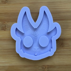 May include: A purple silicone mold shaped like a cartoon goat head with horns, a pentagram, and two round eyes.