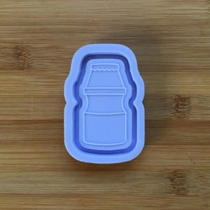 Könnte beinhalten: Eine lila Silikonform zum Backen von Keksen oder Kuchen in Form einer Joghurtflasche.