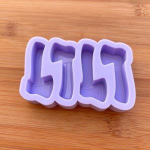 May include: A light purple silicone mould featuring four axe shapes. The mould is designed for crafting, with each axe having a detailed blade and handle. The background is a wooden surface.