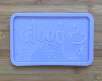 May include: A purple silicone mold with the word "Spooky" in a gothic font. The mold also features three spider web designs and three spider silhouettes.