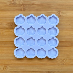 Pode incluir: Um molde de silicone roxo claro com uma grade de dezasseis cavidades idênticas em forma de abóbora. Cada cavidade apresenta cristas verticais detalhadas características de uma abóbora. O texto thecraftsandglittershop.com está impresso no centro.