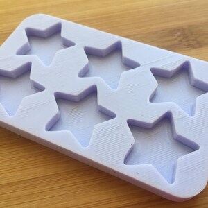 Può includere: Uno stampo in silicone di colore lilla chiaro con sei cavità a forma di stella. Lo stampo è progettato per realizzare piccoli oggetti a forma di stella.