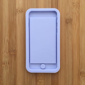 Peut inclure: Un moule en silicone de couleur violet clair en forme de smartphone. Le moule a un bouton en relief en bas et un espace rectangulaire pour un écran.