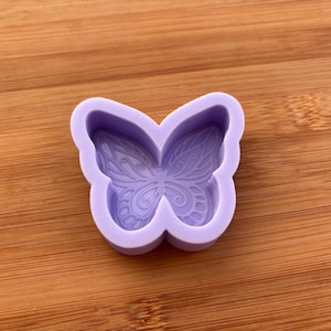Op de afbeelding: Een lavendelkleurige vlindervorm met gedetailleerde vleugelpatronen. De vorm is gemaakt van een flexibel materiaal en is ontworpen voor het maken van decoratieve items. Het vlinderontwerp heeft ingewikkelde lijnen en rondingen.