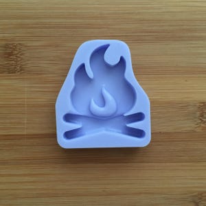 Può includere: Uno stampo in silicone viola a forma di falò con una fiamma al centro. Lo stampo è progettato per realizzare oggetti in resina.