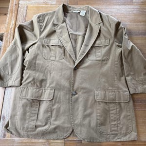 Może przedstawiać: Beżowa marynarka z czterema przednimi kieszeniami, łaty na łokciach i podszewką z siatki. Marynarka ma zapięcie na dwa guziki i rękawy do ¾. Marynarka jest wykonana z miękkiego, trwałego materiału.