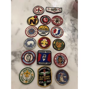 Puede incluir: Una colección de parches bordados vintage, con varios diseños y texto. Los parches incluyen imágenes de un oso, un nativo americano y un conejo. El texto incluye "Blackhawk Area Council", "Camporee" y "Pioneer Trail".
