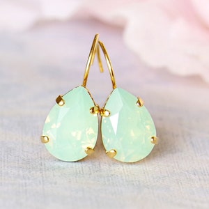 Könnte beinhalten: Ein Paar tropfenförmige Ohrringe mit hellgrünen Opal-Steinen und goldfarbenen Metallfassungen.