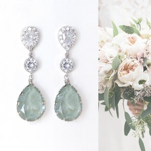 Peut inclure: Une paire de boucles d'oreilles en argent en forme de larme avec un cristal bleu clair et des accents de strass transparents. Les boucles d'oreilles sont pendantes et ont un design délicat.
