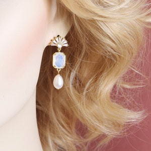 May include: Gold earrings with a white opal stone and a pearl drop.
