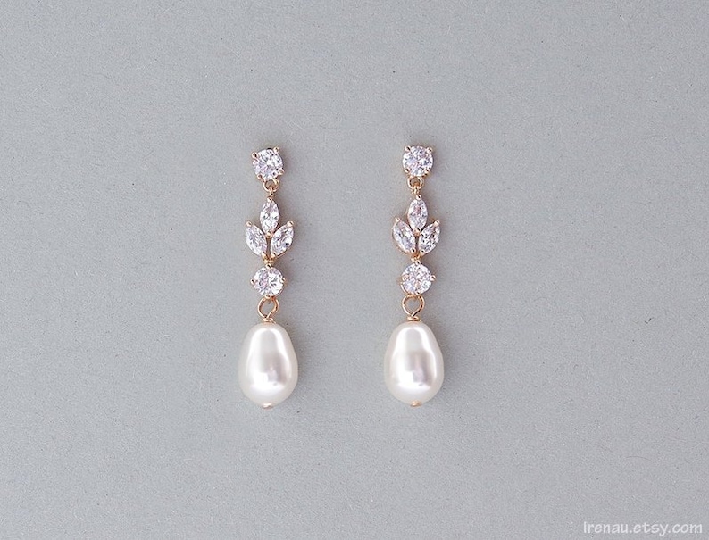 May include: Gold earrings with a pearl drop and a cluster of clear cubic zirconia stones in a leaf design.