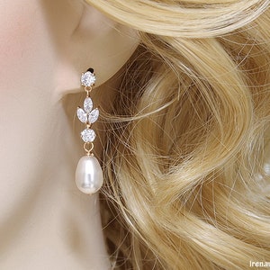 May include: Gold dangle earrings with a pearlescent drop and clear crystal accents.