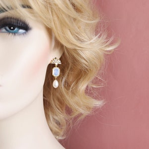 May include: Gold dangle earrings with a blue and white iridescent stone and a pearl drop.