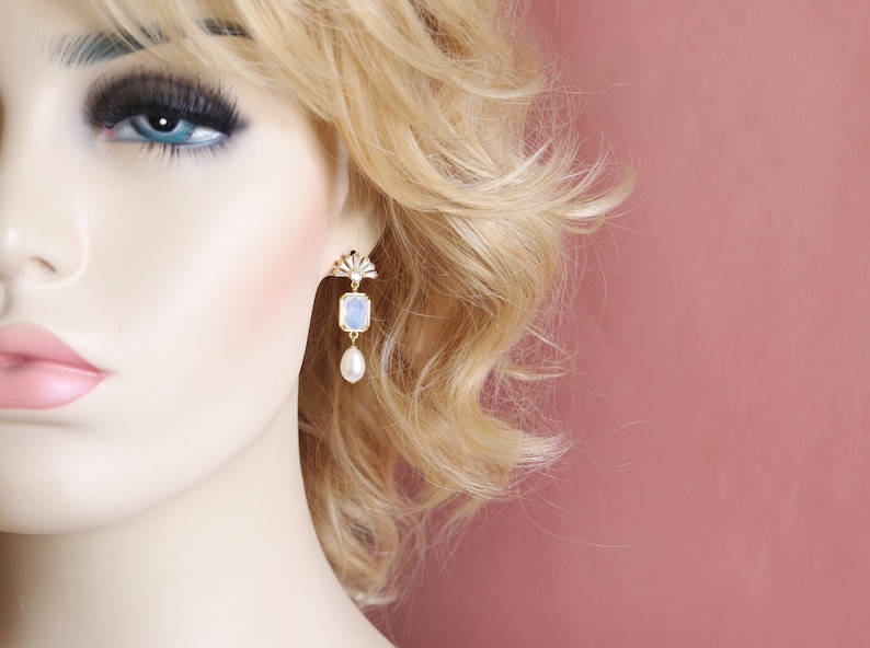 May include: Gold dangle earrings with a blue and white iridescent stone and a pearl drop.