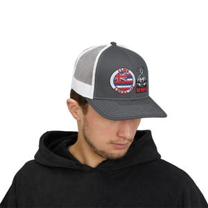 Könnte beinhalten: Eine graue und weiße Trucker-Kappe mit einem Patch, auf dem "I LWU Local 150" steht und eine hawaiianische Flagge abgebildet ist. Der Patch hat auch ein kleines Bild eines Hakens.
