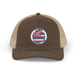Könnte beinhalten: Braune und beigefarbene Trucker-Kappe mit einem runden Patch, der eine hawaiianische Flagge und den Text "ILWU LOCAL 142" zeigt.