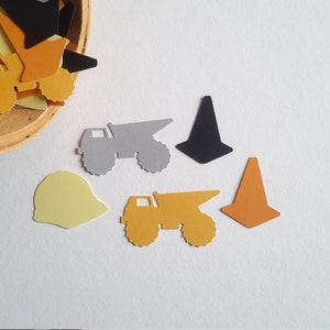 May include: A collection of construction-themed paper cutouts, including dump trucks, cones, and hard hats. The cutouts are in various colours, including yellow, orange, black, and grey.