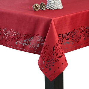 May include: Red tablecloth with a delicate floral lace pattern around the edge. The tablecloth is made of a soft, smooth fabric and is perfect for a holiday dinner.